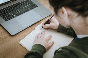 ノートになにか書いている女性